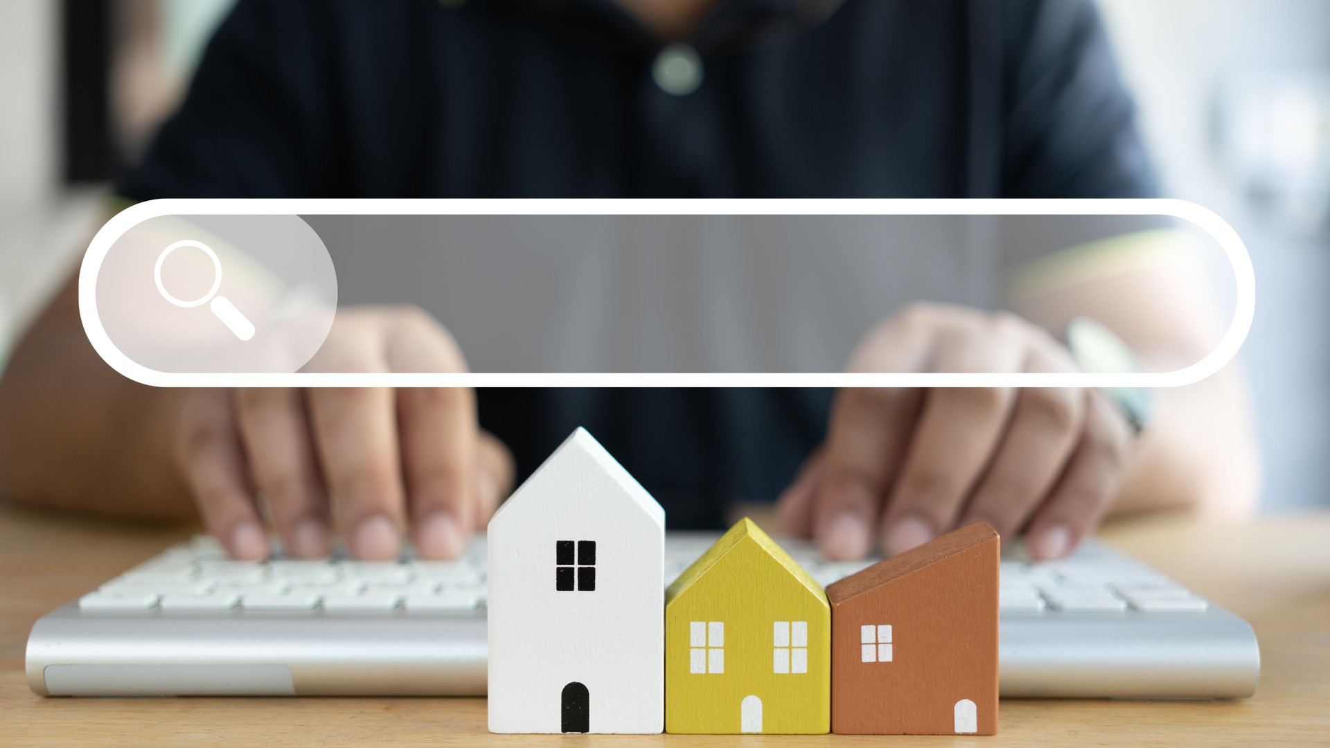 Man using keyboard searching data about the home from browsing internet data Information with a model home in front of.